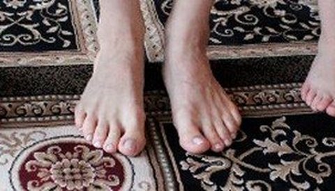 Several pairs of bare feet lined up on a patterned rug