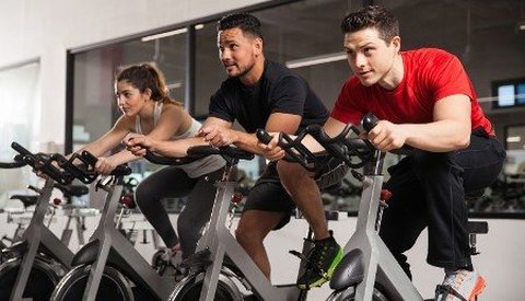 Adults exercising on stationary bikes at a gym