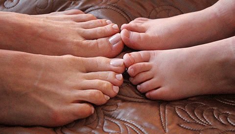 Adult and child feet resting side by side on a sofa